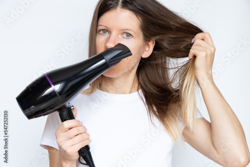 The girl dries her hair with a hairdryer on a white background, hair dryer and hair