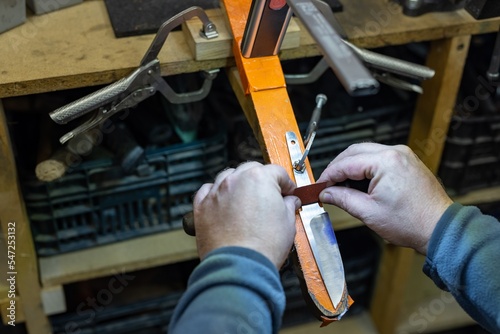 The knife maker shapes and sharpens the newly constructed blade. Production process engineering production.