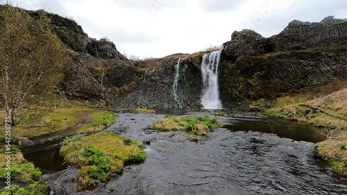 Waterfalls and rock formations in Gjáin valley, Iceland, with volcanic basalt columns and lush vegetation.  photo