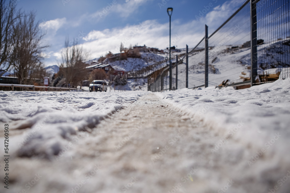 Paisagem com ruas cobertas de neve e montanhas ao fundo