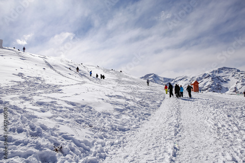 Alto de uma montanha de neve no inverno com pessoas caminhando com roupa apropriada de inverno com dia nublado e sol © Hermes