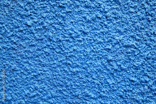 Home facade texture. Rough surface. Grunge grain. Crushed rocks in the wall. Exterior home decoration. Stucco wall pattern. Blue color retro design. Noisy design background.