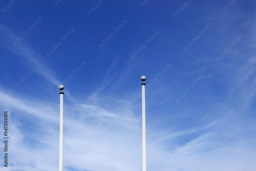 Two white flagpoles under blue sky