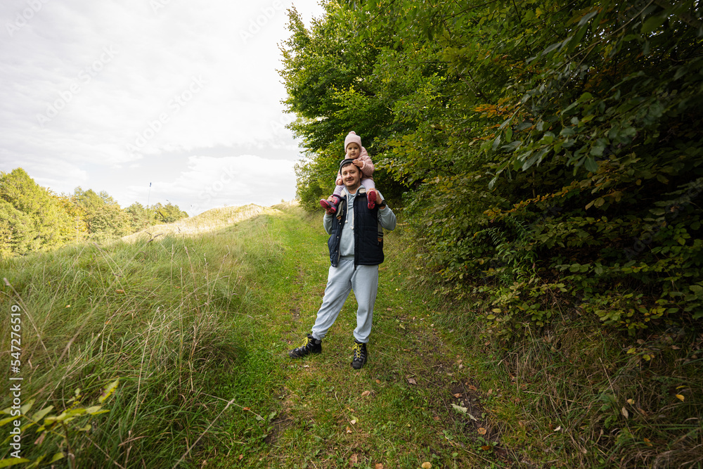 Dad with daughter on his shoulders walking in forest. Dad with daughter on his shoulders walking in forest.