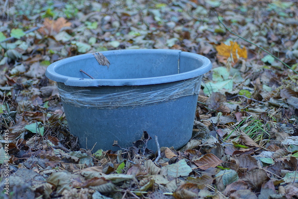 one old gray dirty plastic basin stands on brown dry fallen leaves outdoors in nature one old gray dirty plastic basin stands on brown dry fallen leaves outdoors in nature