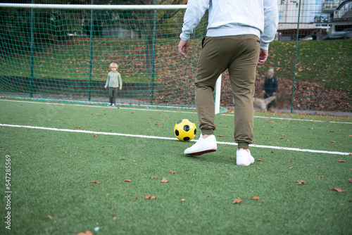 a little boy plays soccer with his father on the soccer field