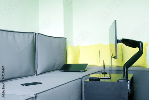Foto Thin monitor next to gray loft sofa, on table and gas lift metal swing arm