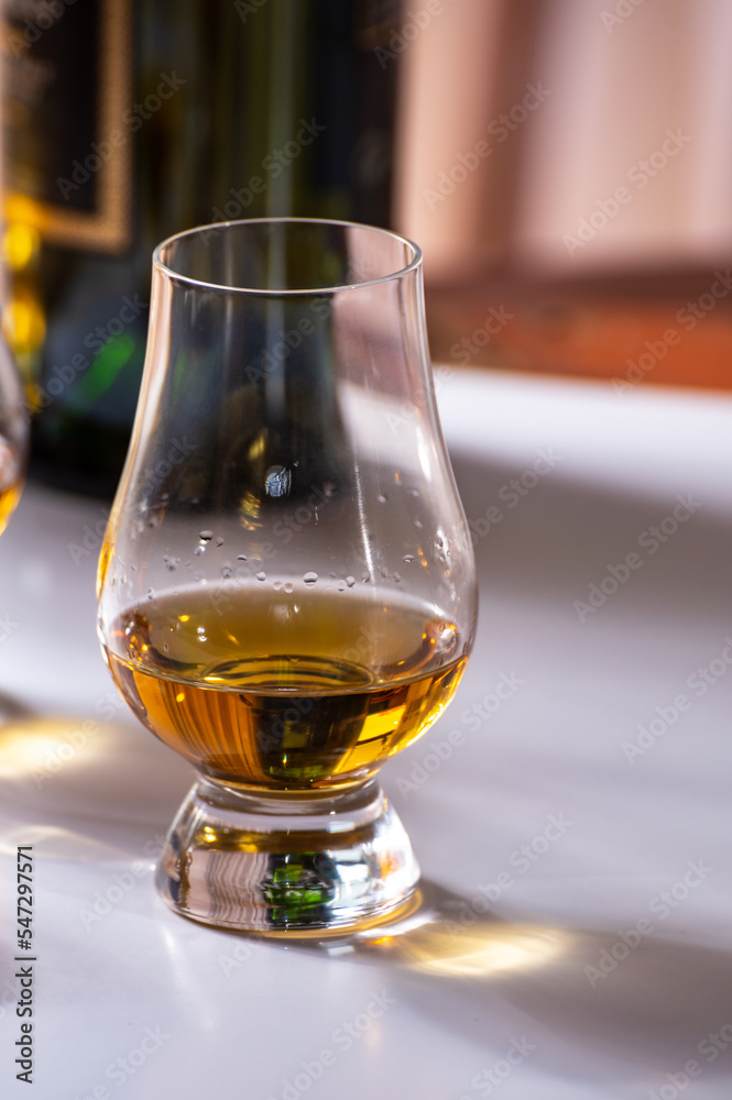 Tasting of whiskey, tulip-shaped tasting glasses with dram of Scotch single malt or blended whisky on white table Tasting of whiskey, tulip-shaped tasting glasses with dram of Scotch single malt or blended whisky on white table