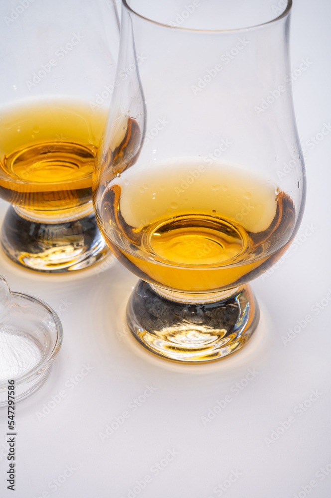 Tulip-shaped tasting glass with dram of Scotch single malt or blended whisky on white background Tulip-shaped tasting glass with dram of Scotch single malt or blended whisky on white background