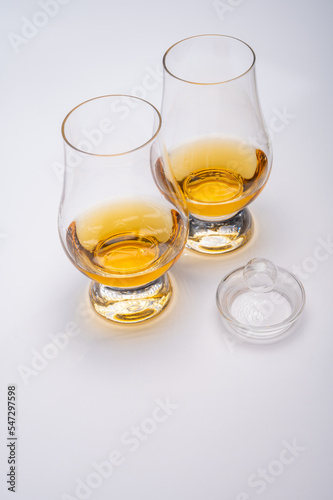 Tulip-shaped tasting glass with dram of Scotch single malt or blended whisky on white background © barmalini