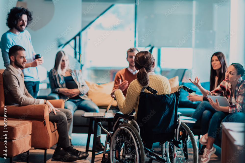Obraz premium Businesswoman in wheelchair having business meeting with team at modern office. A group of young freelancers agree on new online business projects