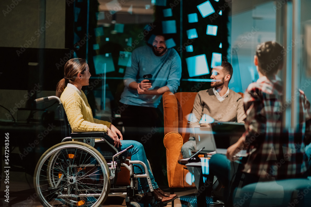 Businesswoman in wheelchair having business meeting with team at modern office. A group of young freelancers agree on new online business projects