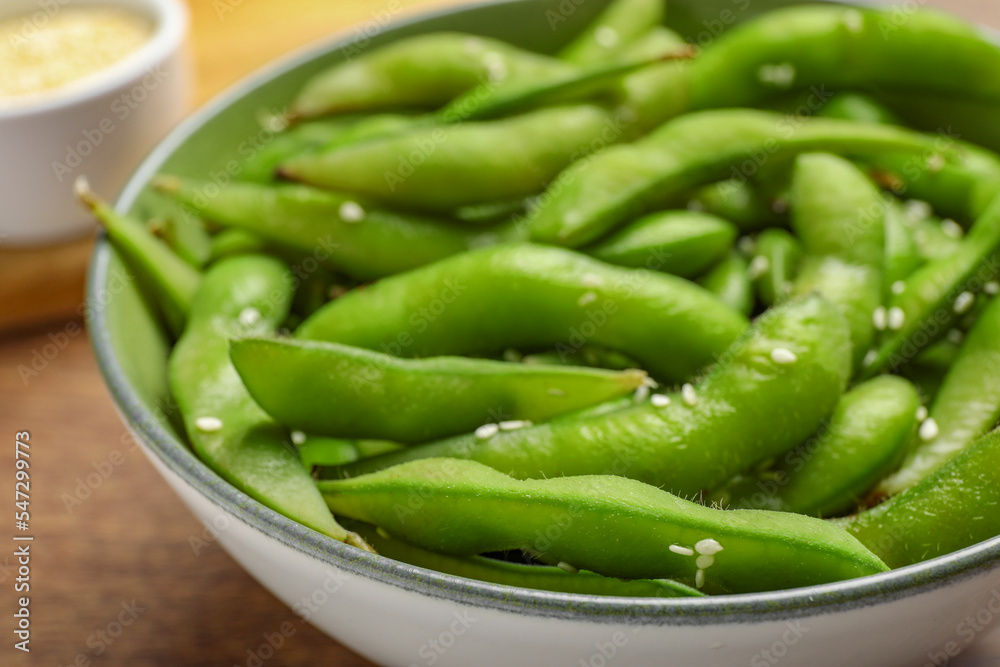 Bowl with green edamame beans in pods on wooden table, closeup Bowl with green edamame beans in pods on wooden table, closeup