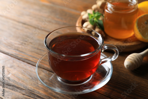 Cup of delicious ginger tea and ingredients on wooden table