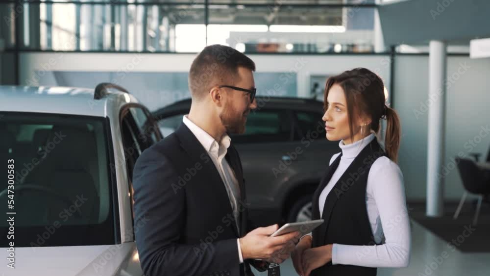 Electronic signature when buying a rental car, a young woman signs in a tablet at a car dealership Electronic signature when buying a rental car, a young woman signs in a tablet at a car dealership