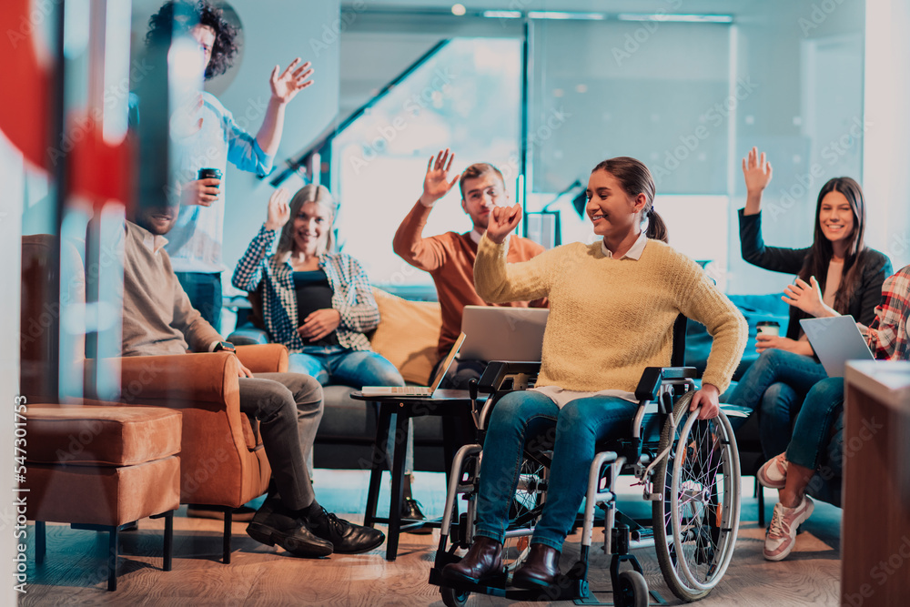 Businesswoman in wheelchair having business meeting with team at modern office. A group of young freelancers agree on new online business projects