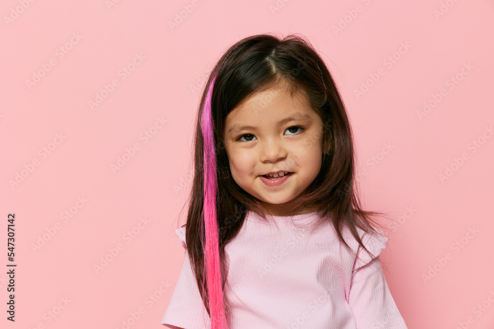pleasant, sweet, joyful girl with a false strand of pink color in her hair smiling looking at the camera pleasant, sweet, joyful girl with a false strand of pink color in her hair smiling looking at the camera