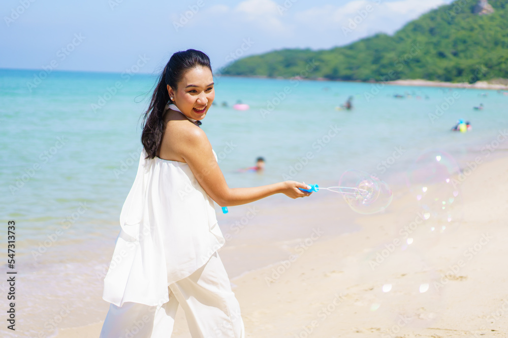 Happy Asian woman enjoy playing with a soap bubble at the beach.
