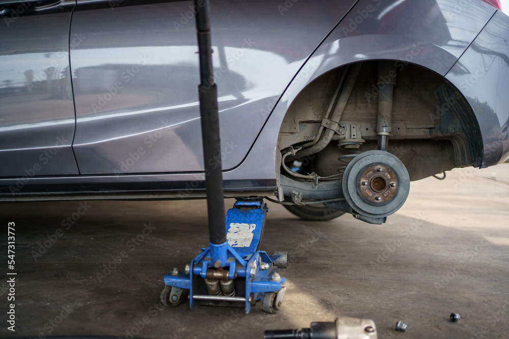 Foto de Technician or repairman using a hydraulic jack lift up a car at
