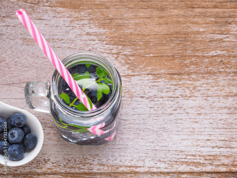 Infused water with fresh organic blueberries and drinking straw on wooden background. Space for your text. Top view, flat lay.. Infused water with fresh organic blueberries and drinking straw on wooden background. Space for your text. Top view, flat lay..