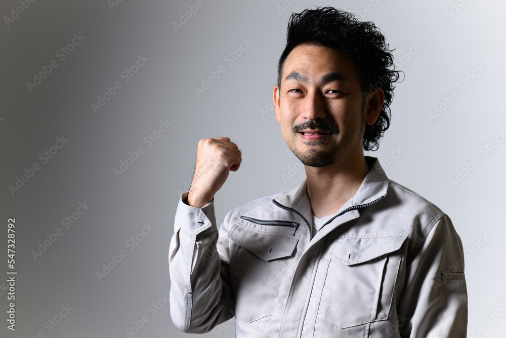 ガッツポーズで笑顔の頼れそうな作業着の中年男性 ガッツポーズで笑顔の頼れそうな作業着の中年男性