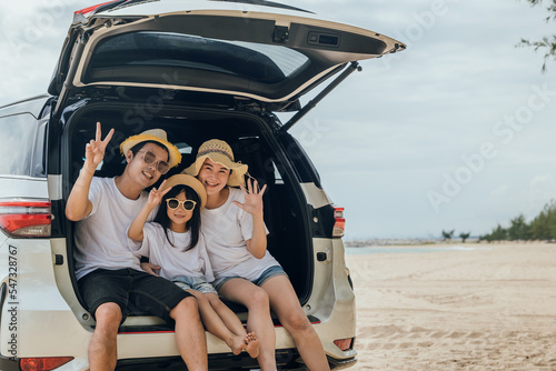 Tourism Day. Family having fun in summer vacation on beach show V-sign finger. Parents and kid family travel in holiday at sea beach. Father, Mother and daughter enjoying road trip sitting on back car © sorapop