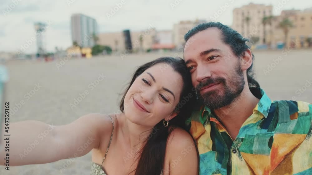 Close-up of romantic couple taking selfie on mobile phone while sitting on the beach Close-up of romantic couple taking selfie on mobile phone while sitting on the beach