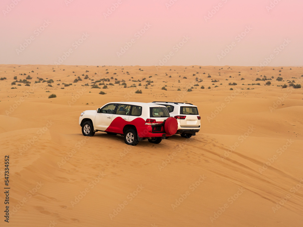 Group of off-road cars on desert dunes at sunset. Desert tour for tourists at United Arab Emirates Group of off-road cars on desert dunes at sunset. Desert tour for tourists at United Arab Emirates