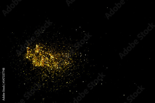 Gold glitter powder sparkling on black background.texture christmas