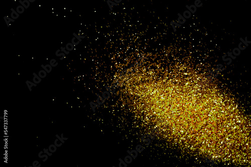 Gold glitter powder sparkling on black background.texture christmas