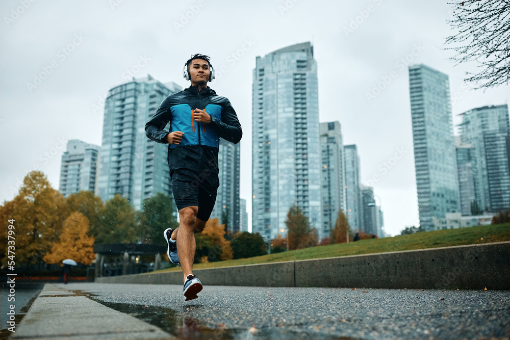Below view of motivated sportsman running outdoors in rain.