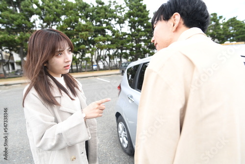 Foto 車の前で喧嘩する男女の若いカップル