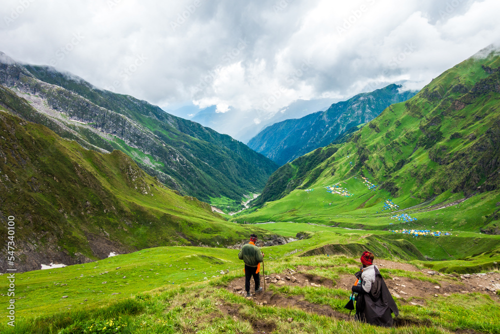 July 14th 2022, Himachal Pradesh India. People with a walking stick trekking down to Parvati bagh valley during Shrikhand Mahadev Kailash Yatra in the Himalayas.