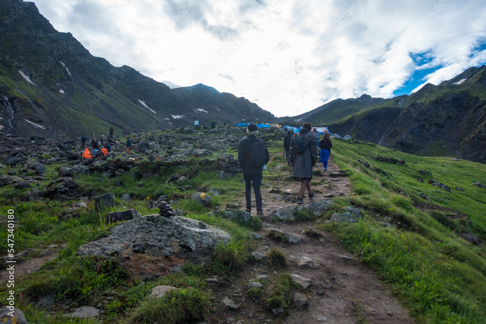 July 14th 2022, Himachal Pradesh India. People with backpacks and walking sticks trekking during Shrikhand Mahadev Kailash Yatra in the Himalayas.