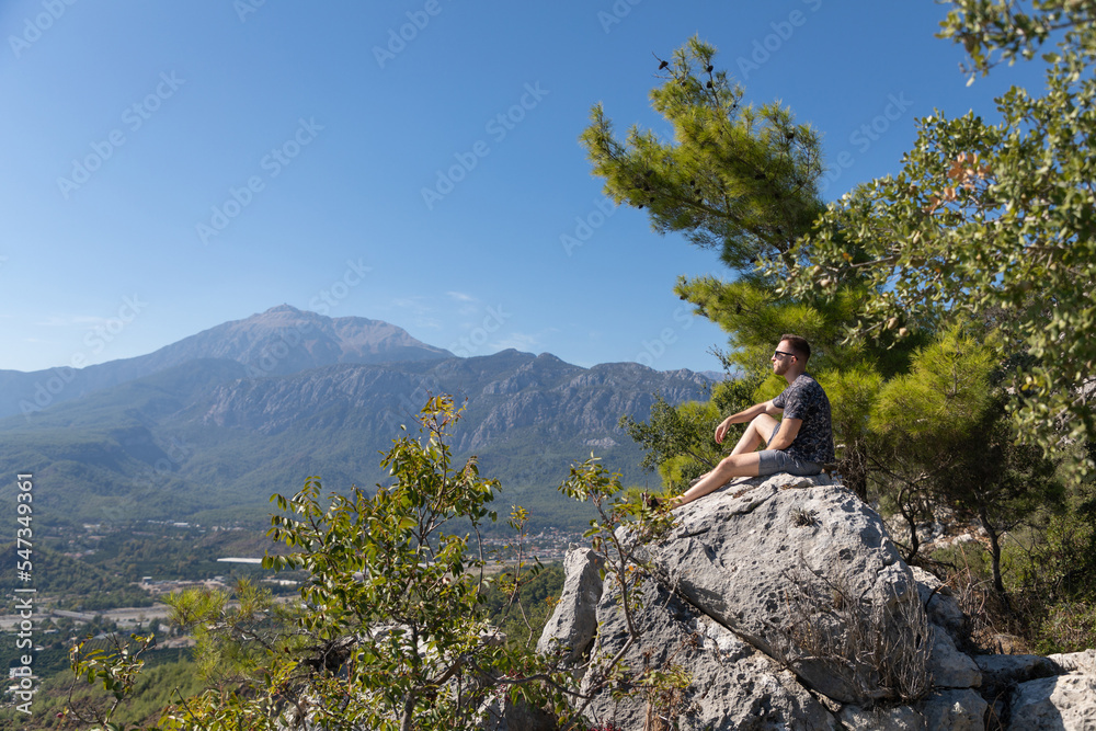 The man on a mountaintop admiring the surrounding mountain landscape