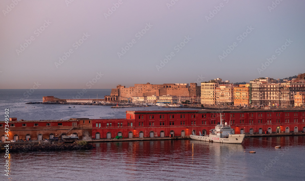 Navy Warship at a port with Historic Downtown City on Mediterranean Coast of Naples, Italy. Sunrise Sky.