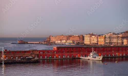Navy Warship at a port with Historic Downtown City on Mediterranean Coast of Naples, Italy. Sunrise Sky.