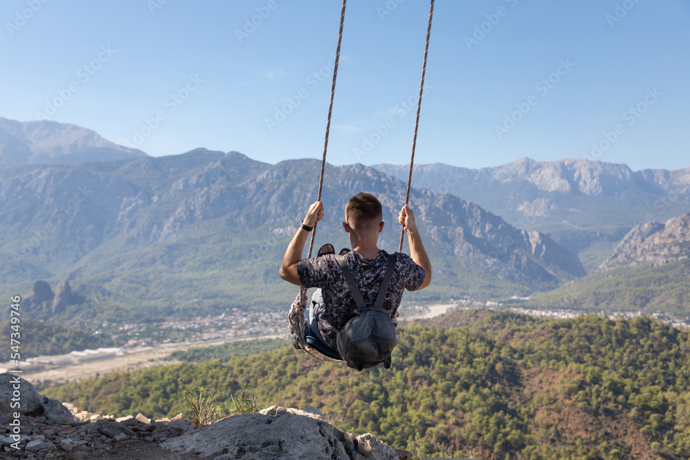 The traveler man on a swing on top of a mountain