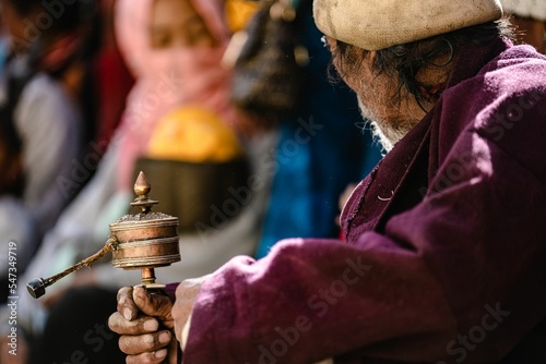 Selective focus shot of senior man holding Tibetan Buddhist Prayer wheel at Tiji Festival photo