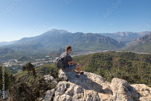 The man on a mountaintop admiring the surrounding mountain landscape