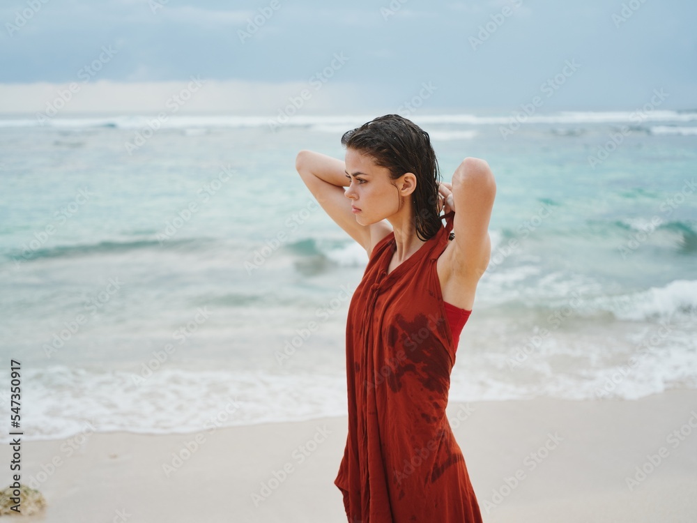 Woman freezes after swimming in the ocean and puts on clothes in cloudy overcast weather Woman freezes after swimming in the ocean and puts on clothes in cloudy overcast weather