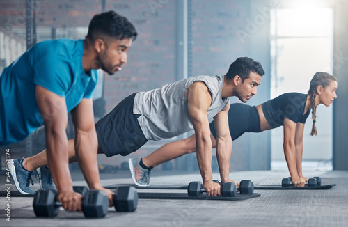 Fitness  teamwork and group with weights  focus and training for a body goal together in the gym. Exercise  power and strong friends in a kettlebell class for a strength training workout at a club