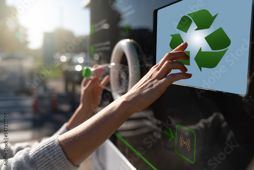 Woman uses a self service machine to receive used plastic bottles and cans on a city street	