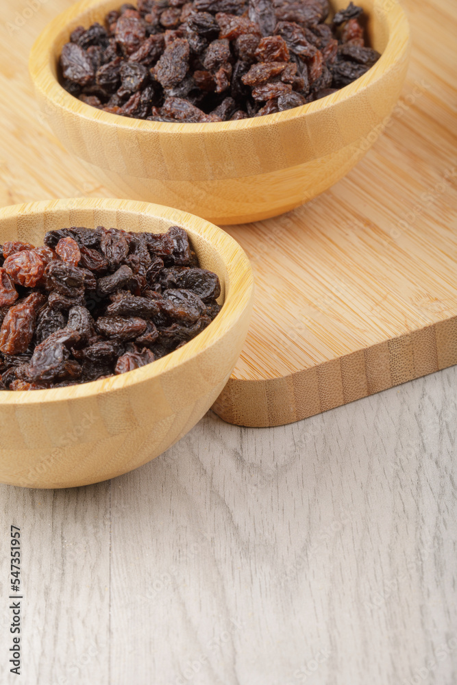Wooden bowls of delicious dried raisins on a wooden table Wooden bowls of delicious dried raisins on a wooden table