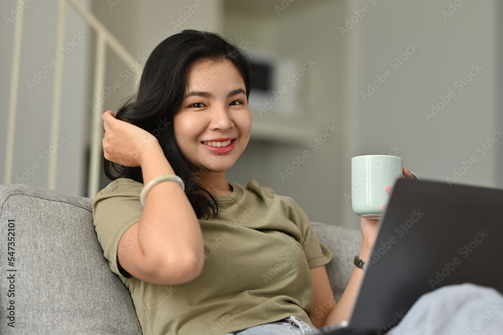 Smiling Young Asian woman using laptop, sitting on couch at home, Shopping online, Chatting in social network, Watching movie or freelancer working on computer. Smiling Young Asian woman using laptop, sitting on couch at home, Shopping online, Chatting in social network, Watching movie or freelancer working on computer.