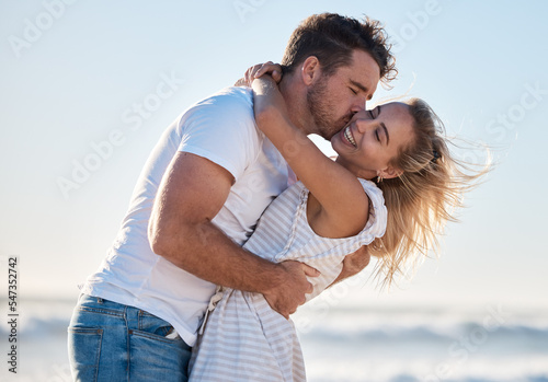 Love, dating and couple kiss at beach enjoying summer holiday, vacation and honeymoon by the sea. Travel, romance and man and woman show affection, embrace and bonding in nature on weekend together