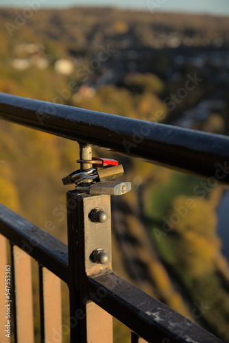Love locks on a railing on a viewing platform in a rural setting over a valley with a river