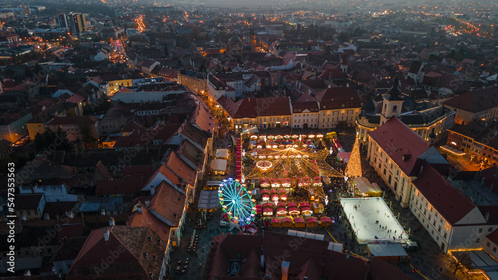 Landscape photography of Sibiu city center with the Christmas Fair, shot from a drone at sunset with the city lightning on. Birds eye view over cityscape of Sibiu, Romania.
