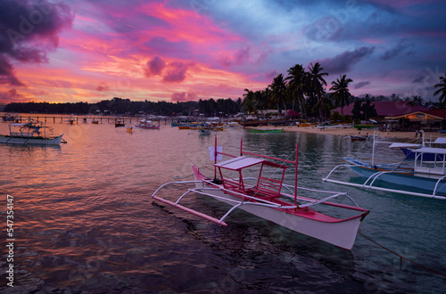 Beautiful colorful sunset on the seashore with fishing boats. Philippines, Siargao Island. photo