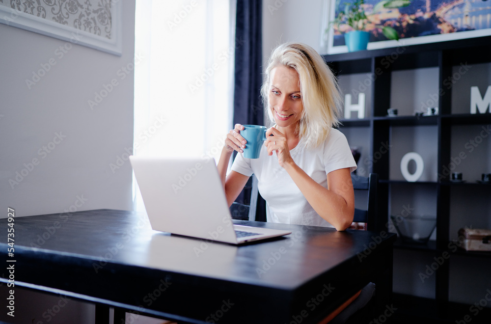 Working at home. Young woman using laptop computer while sdrinking coffee. Working at home. Young woman using laptop computer while sdrinking coffee.
